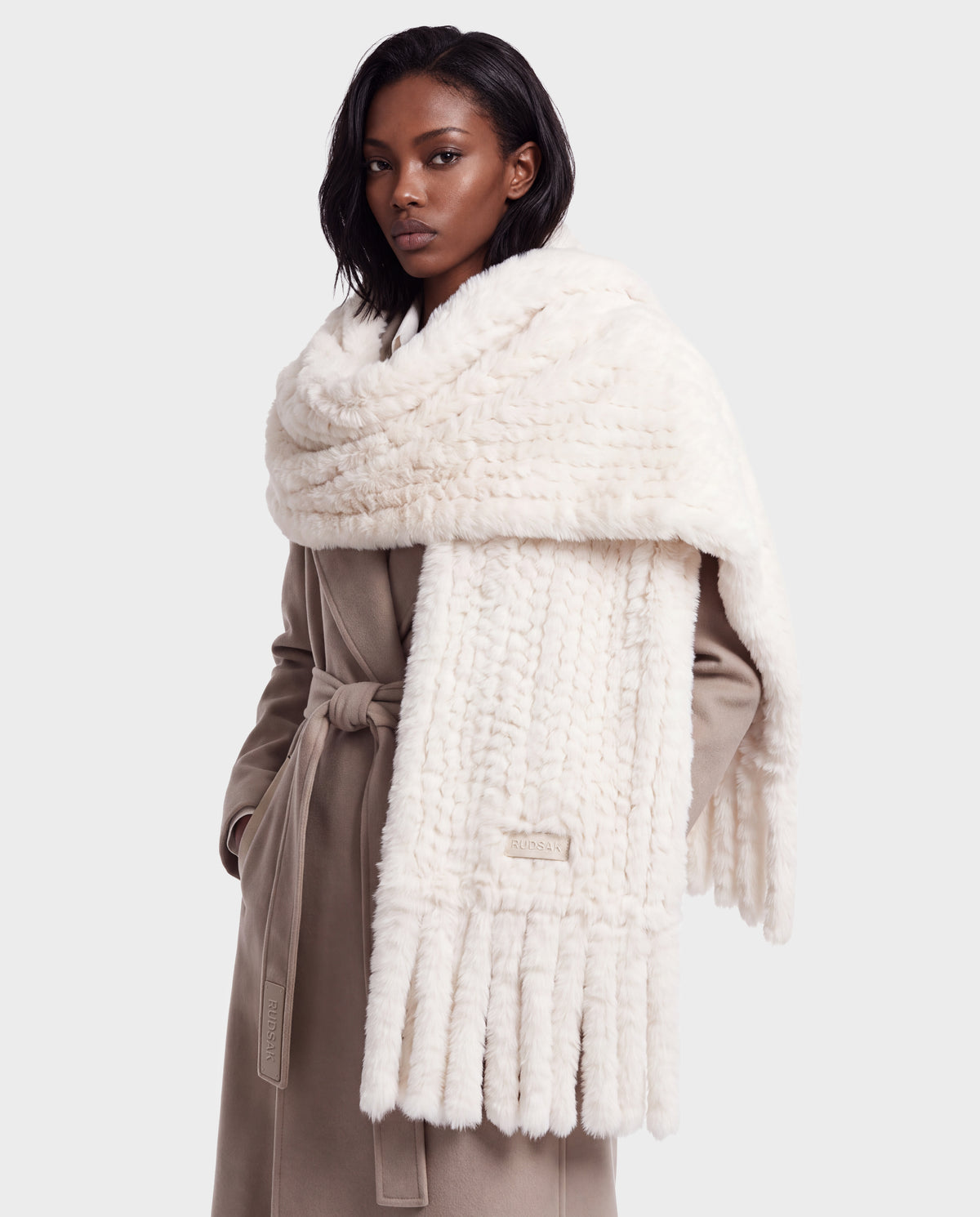 A person wearing a tan wrap coat and a TAVIA - 8426511 Vanilla off-white chunky knit scarf with a fringed hem, perfect for cold-weather styling.