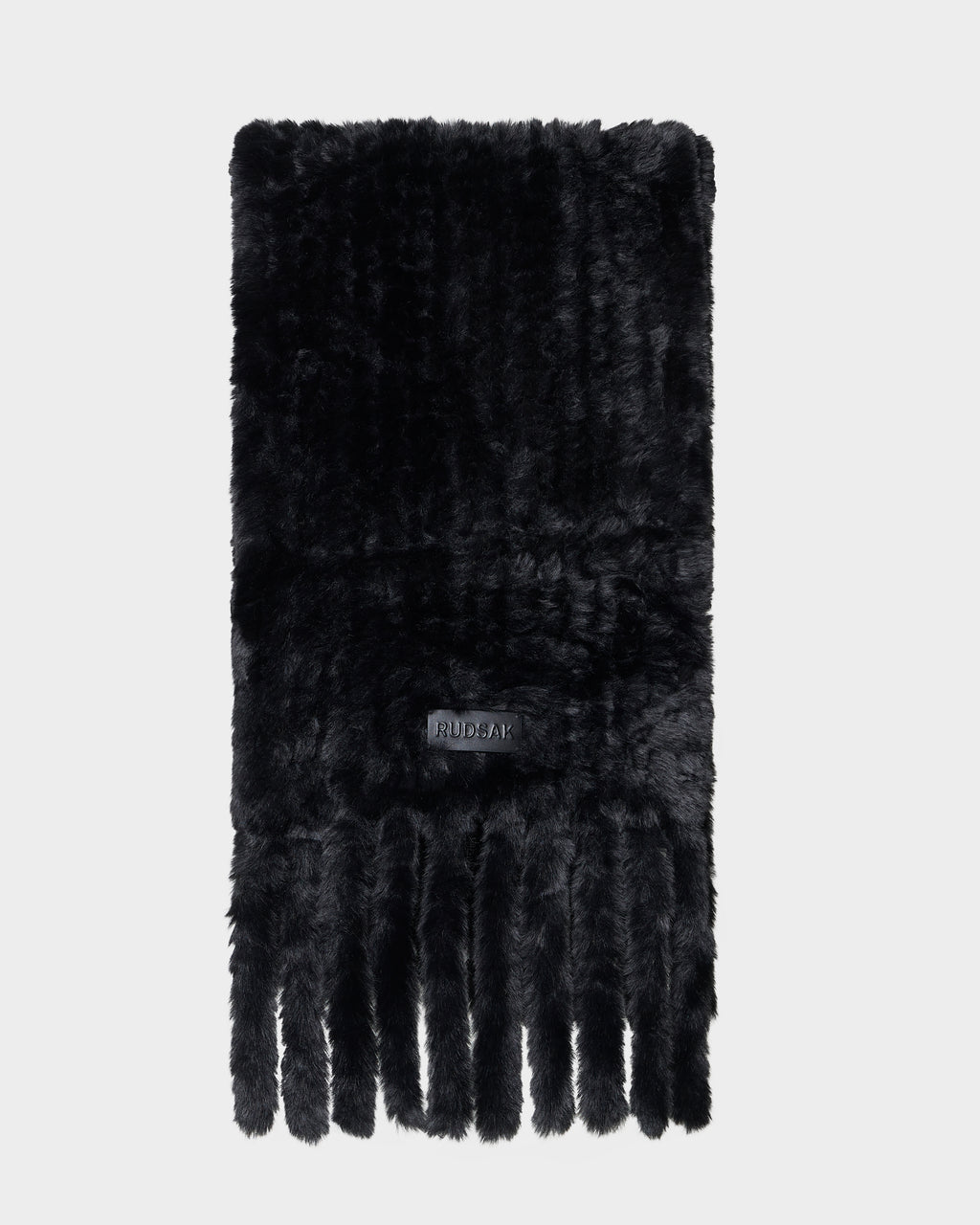 The TAVIA - 8426511 Black scarf by Rudsak is a black faux fur accessory with a soft texture, adorned with a label and multiple long fringes at the ends, displayed on a plain white background.