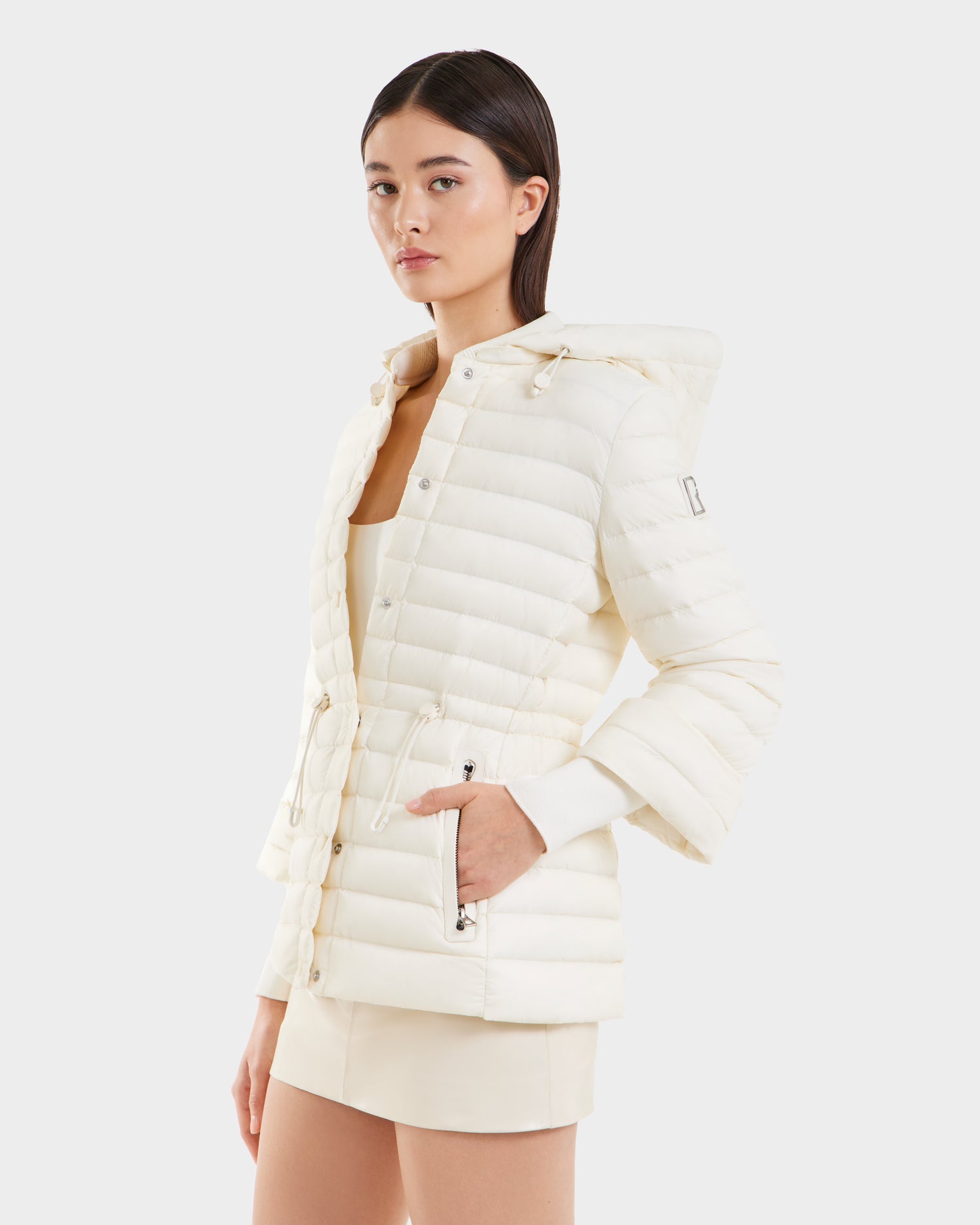 A woman wearing Rudsaks AMAYAH - L125015 Iceland, a lightweight down jacket designed with a feminine silhouette.