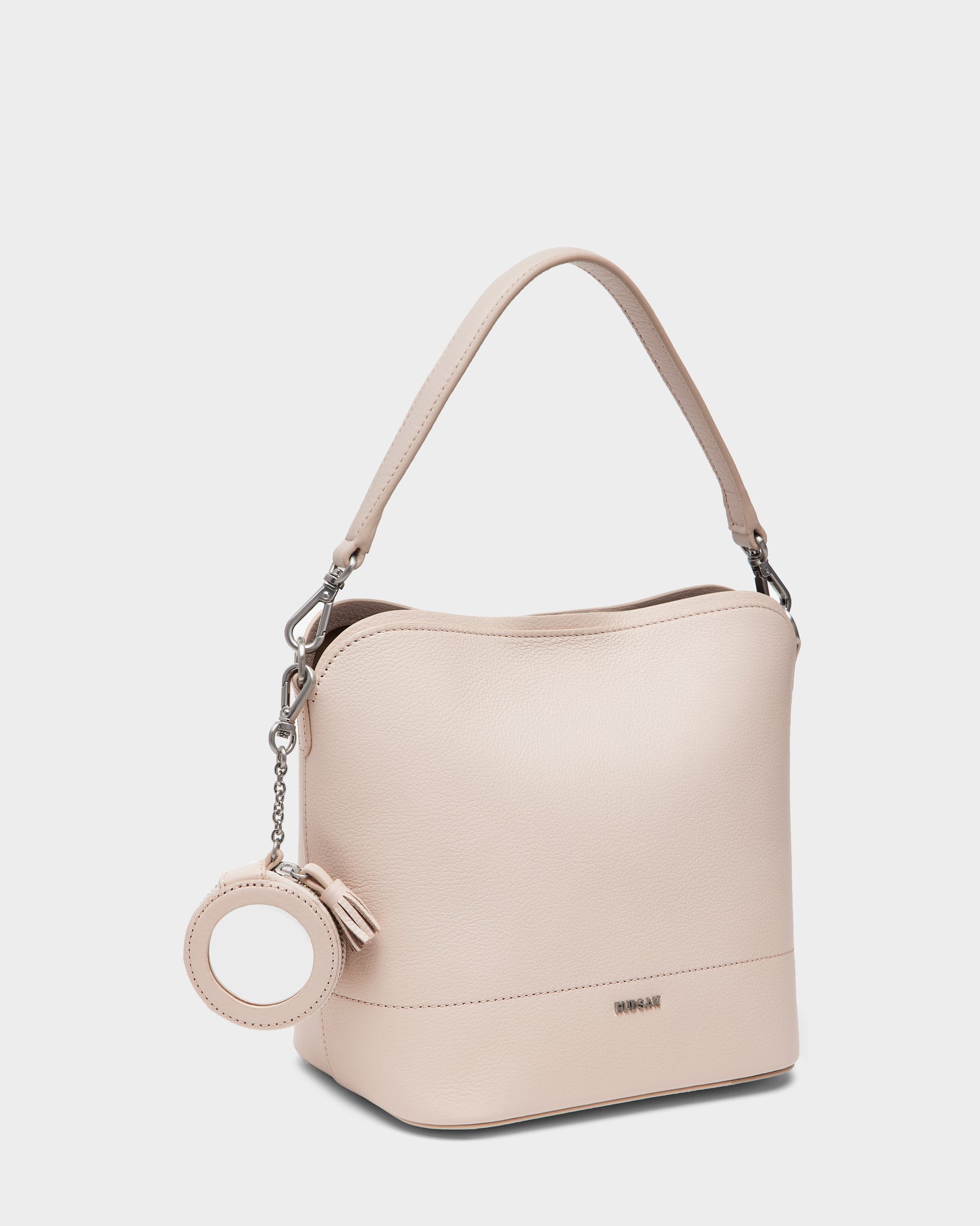 A soft pink women’s pebble leather hobo bag by Rudsak with a single handle, silver hardware, and a small round matching accessory on a chain; the model is ANIA SM - 8325009.