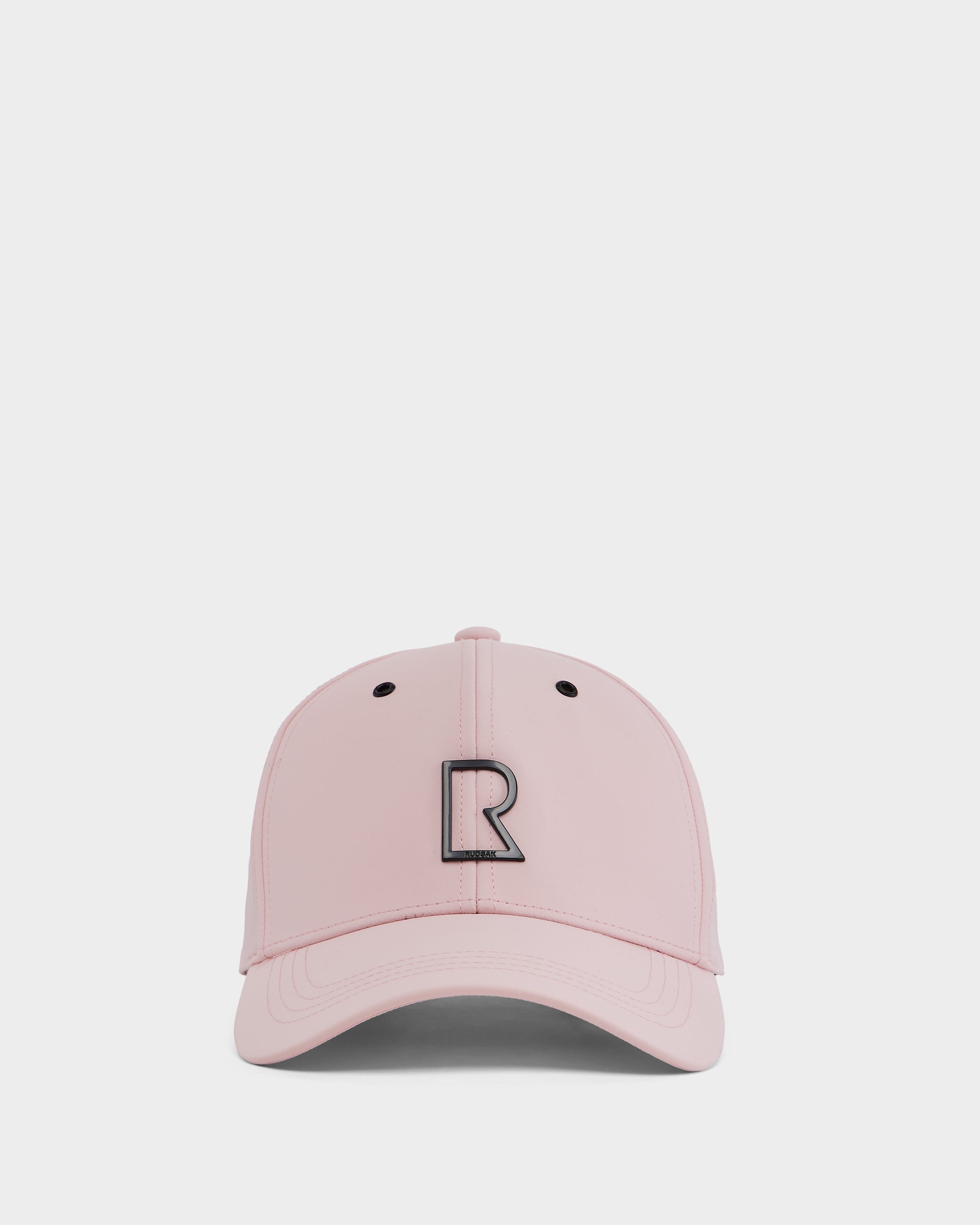 The Rudsak ARSENE - 9422504 Light Pink cap is a unisex, adjustable baseball hat with a curved brim and bold black R logo on the front, shown against a plain white background.