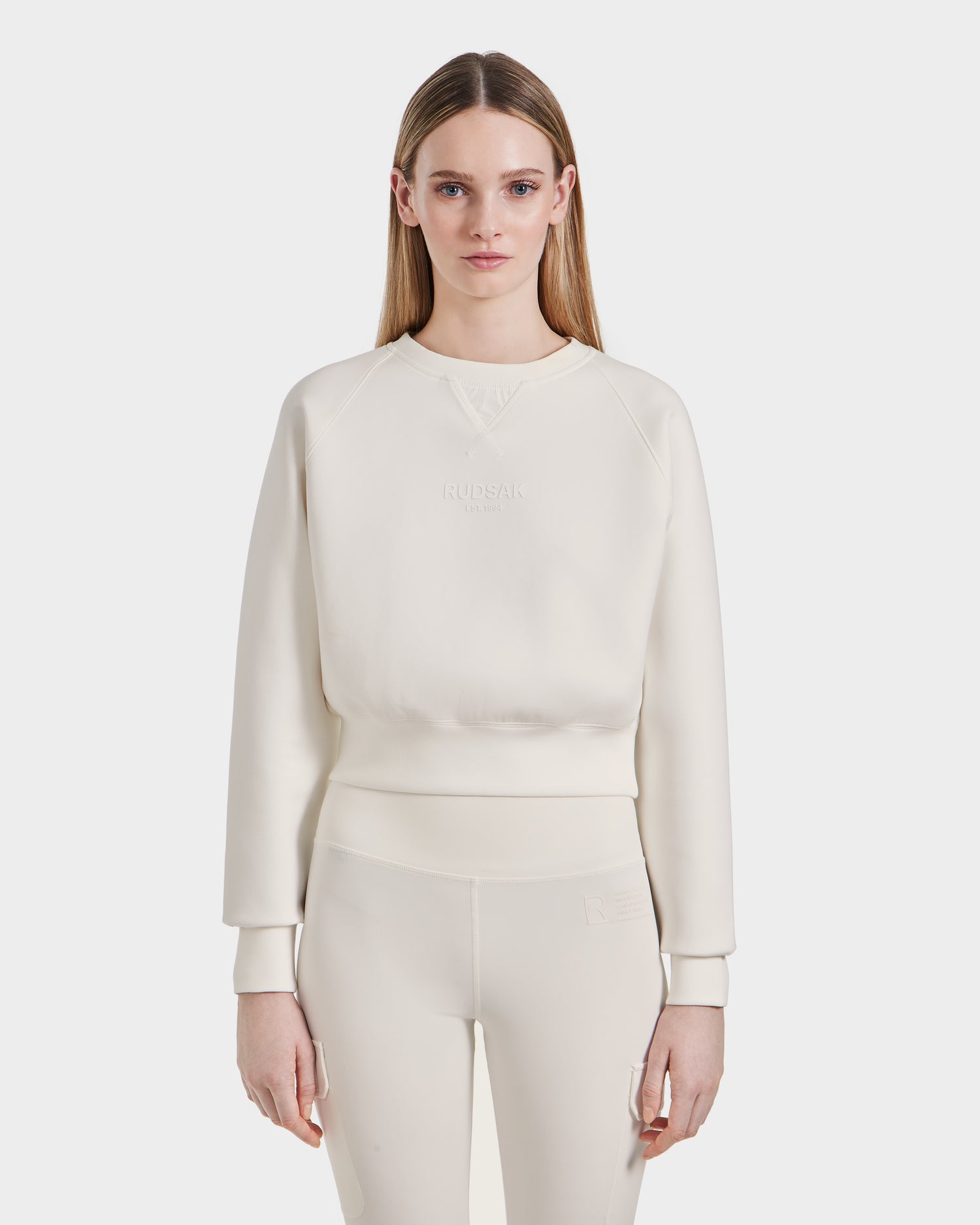 A woman with straight, light brown hair wears the Rudsak BETSY - 8525087 Iceland premium cotton blend crewneck sweater and matching leggings, standing against a plain white background and facing forward with a neutral expression.