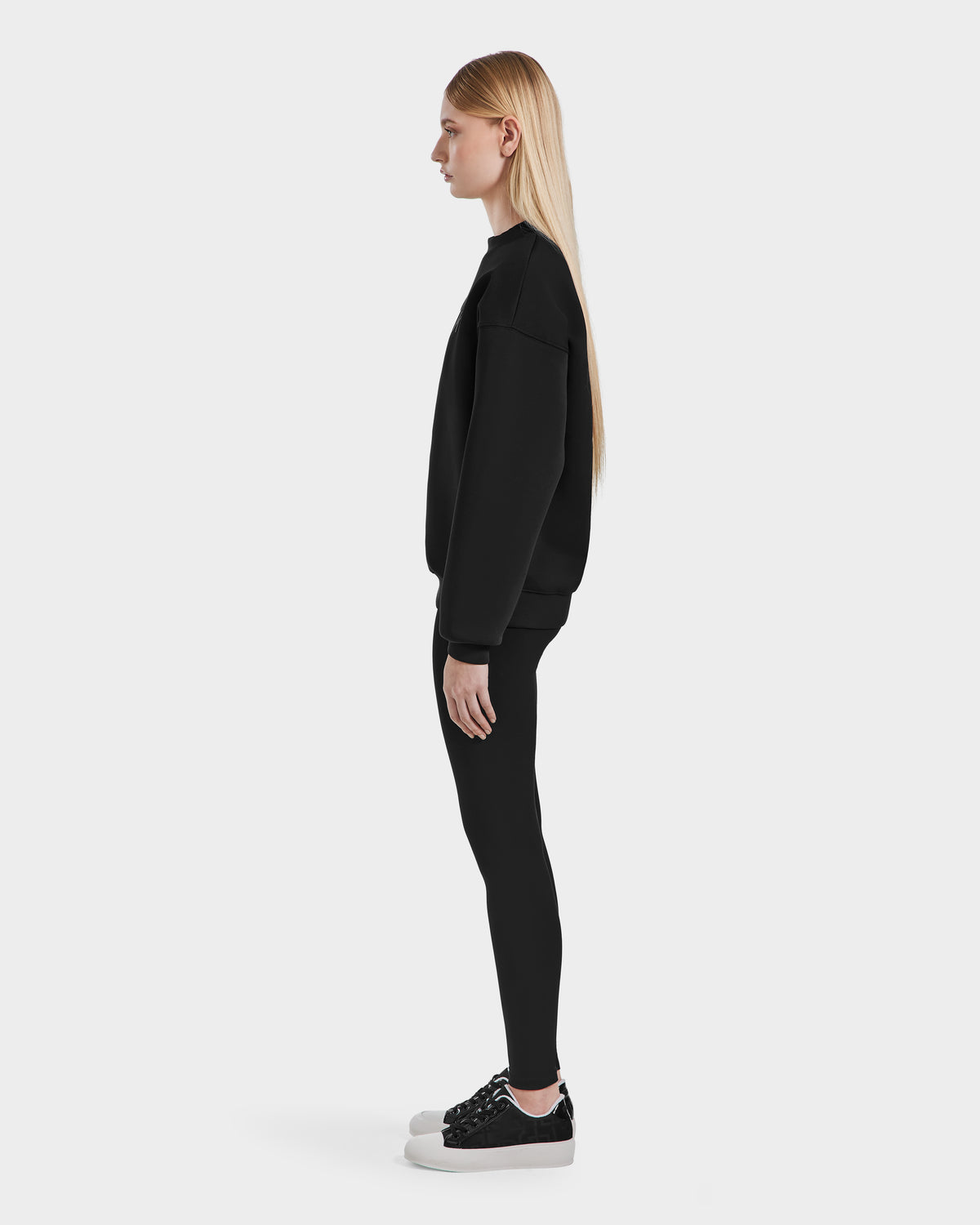 A woman wears the Rudsak BRYN - 9524007 Black W cotton crewneck sweatshirt, highlighting its blend of comfort and effortless style for everyday wear.