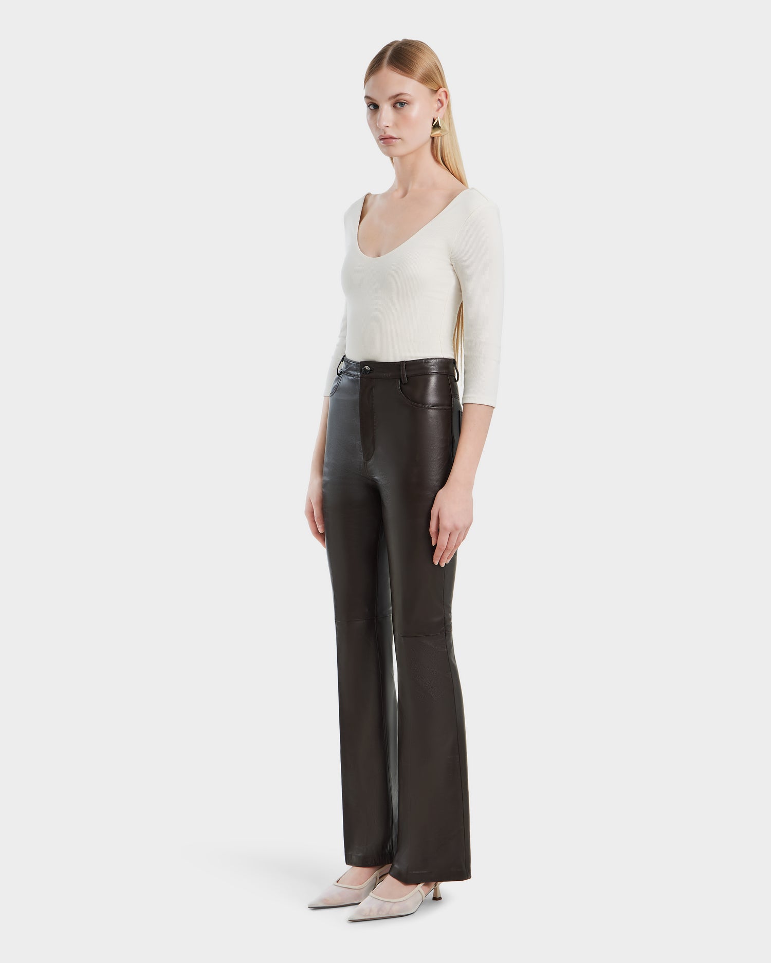 A woman wearing the Rudsak CARISSA - 8524545 Espresso leather pants and a white shirt.