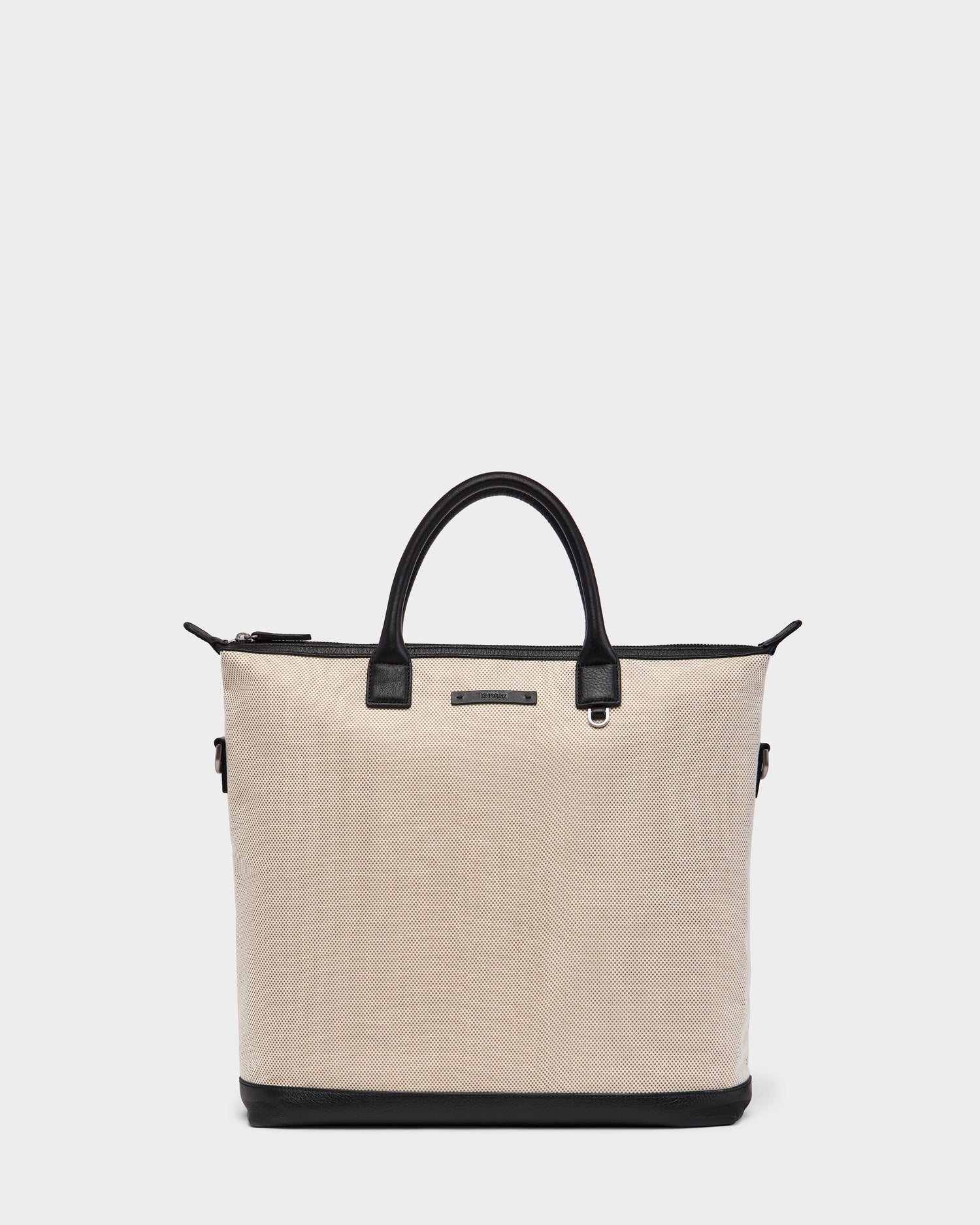 The DEXTER - 9324513 Vanilla by Rudsak is a beige textured canvas tote with black leather handles, black trim, and base. Featuring a zipper closure and front metal label, this unisex bag is a versatile accessory for any occasion.