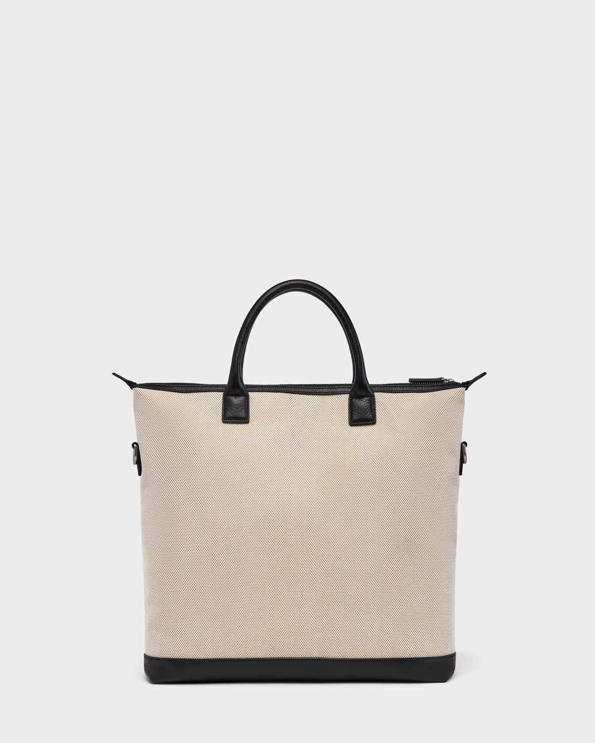 The Rudsak DEXTER - 9324513 Vanilla is a beige canvas tote with black leather handles, trim, and base. Its zippered top and rectangular shape make this unisex bag a versatile accessory for any occasion. Displayed on a plain white background.