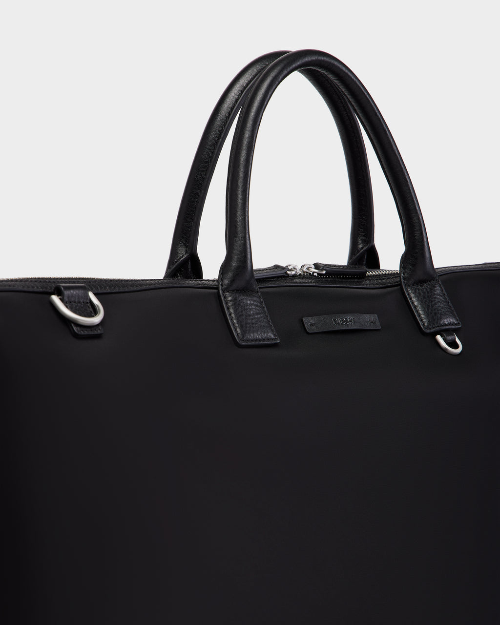 A close-up of the Rudsak DUBLIN - 9324514 Black canvas leather bag with silver hardware, featuring two sturdy handles and a zippered top—ideal as a unisex travel bag, set against a plain light background.