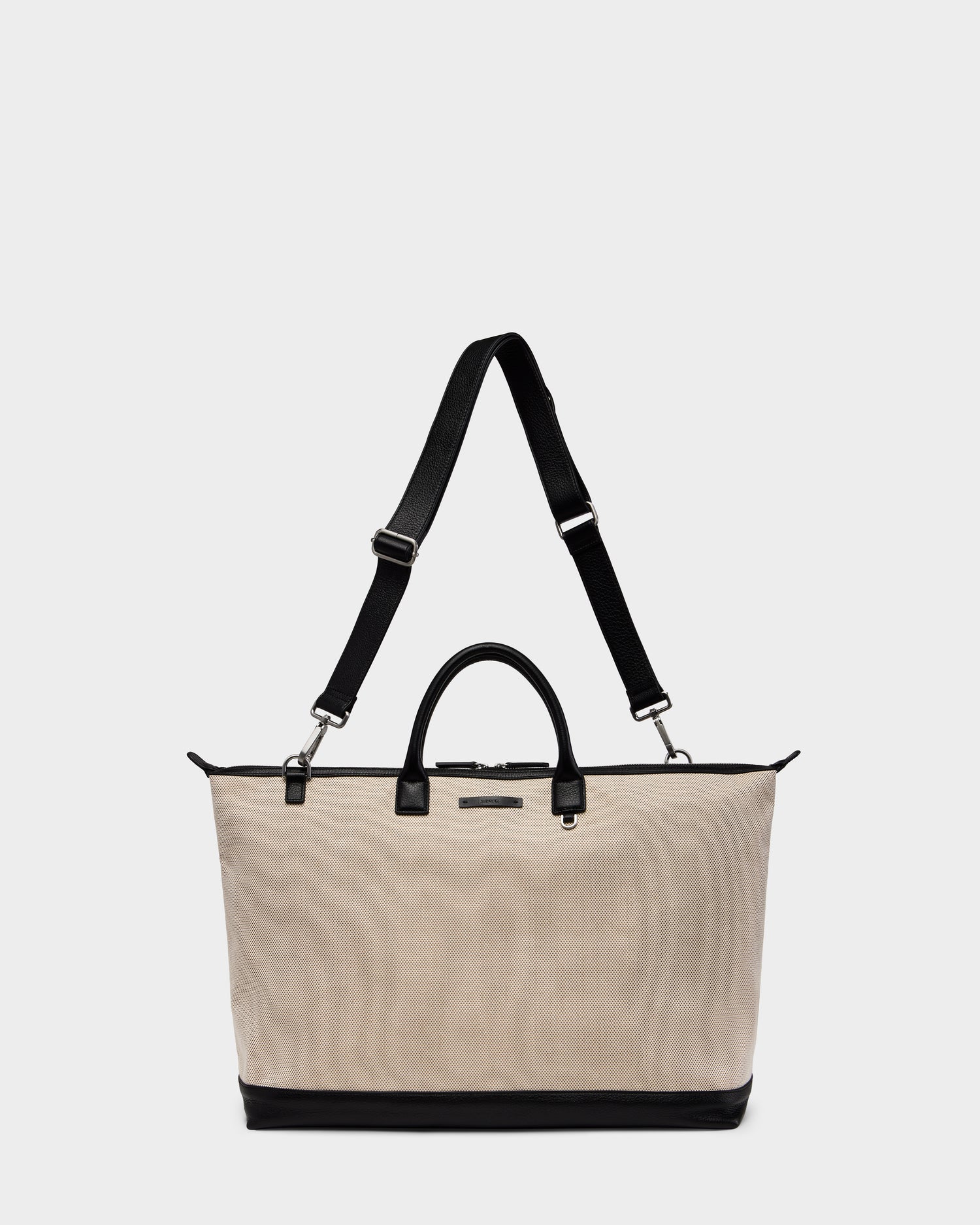 The Rudsak DUBLIN - 9324514 Vanilla is a unisex canvas leather tote with black handles, an adjustable shoulder strap, and sturdy black base—ideal as a weekender bag, shown against a plain white background.