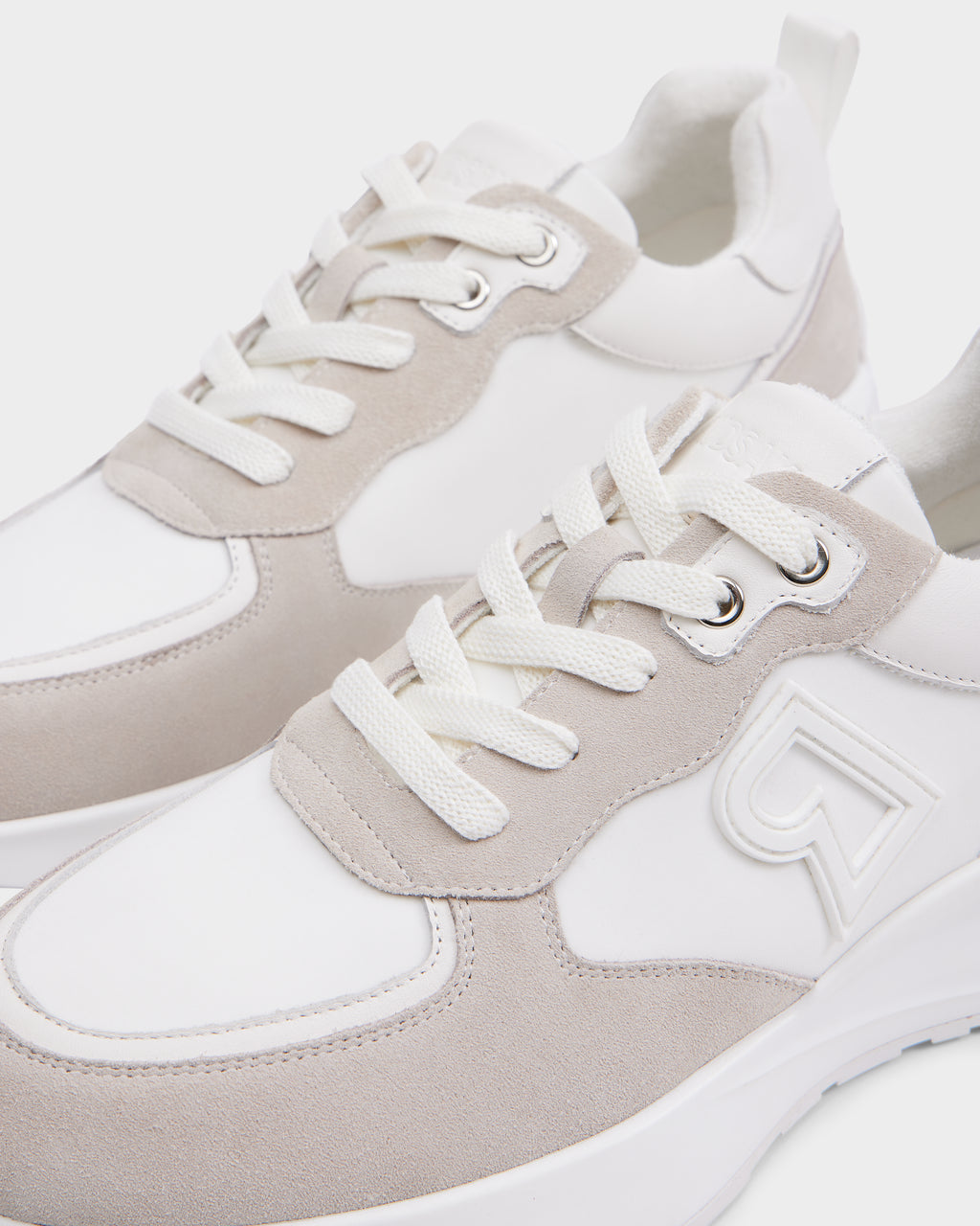 A close-up of the Rudsak LIONEL - 6225001 Iceland men’s sneaker in white and beige, featuring durable suede and fabric panels, white laces, and a raised side logo for a contemporary style.