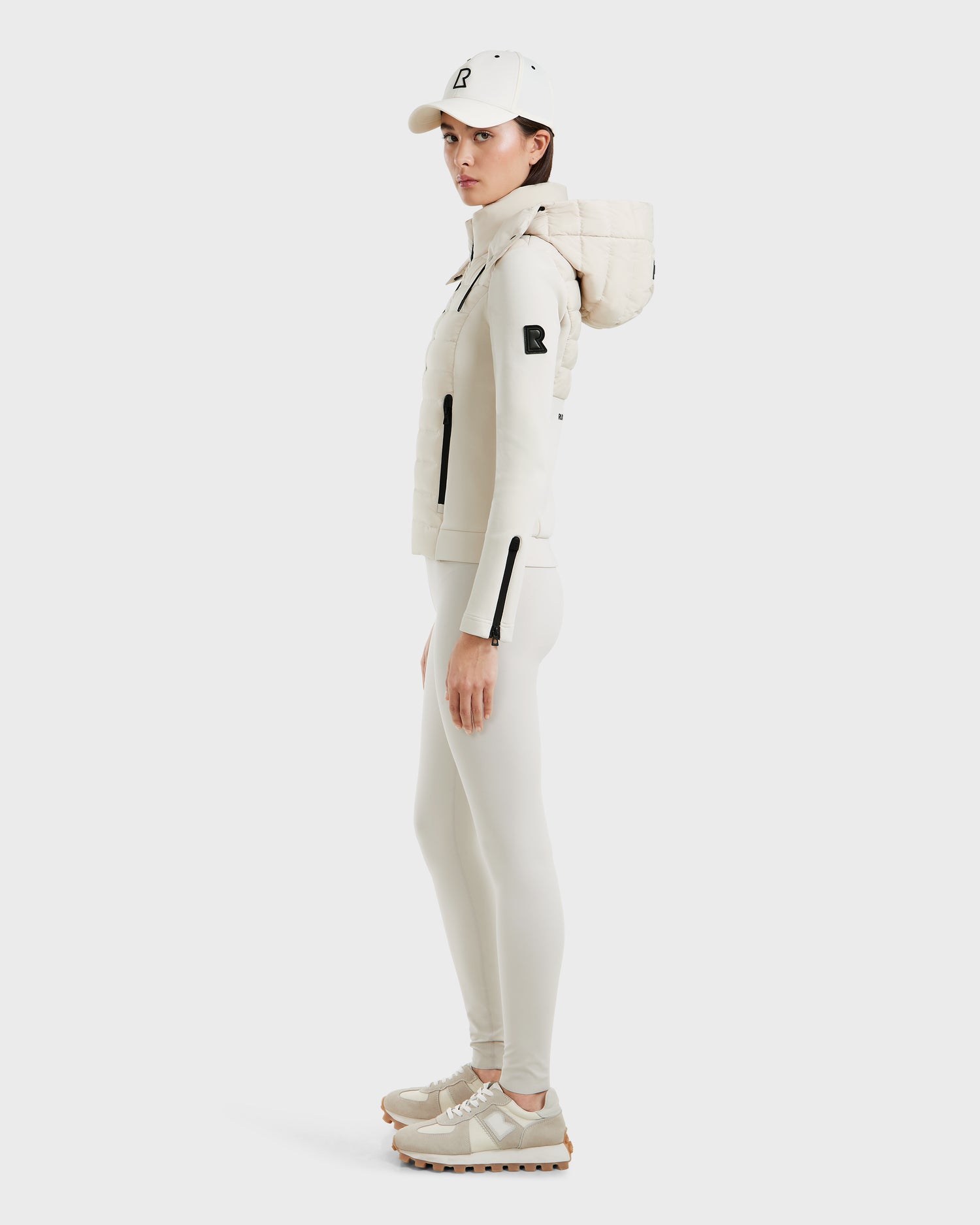 A woman stands in profile against a plain white background, wearing the Rudsak MABS - 8125055 Vanilla lightweight activewear jacket.