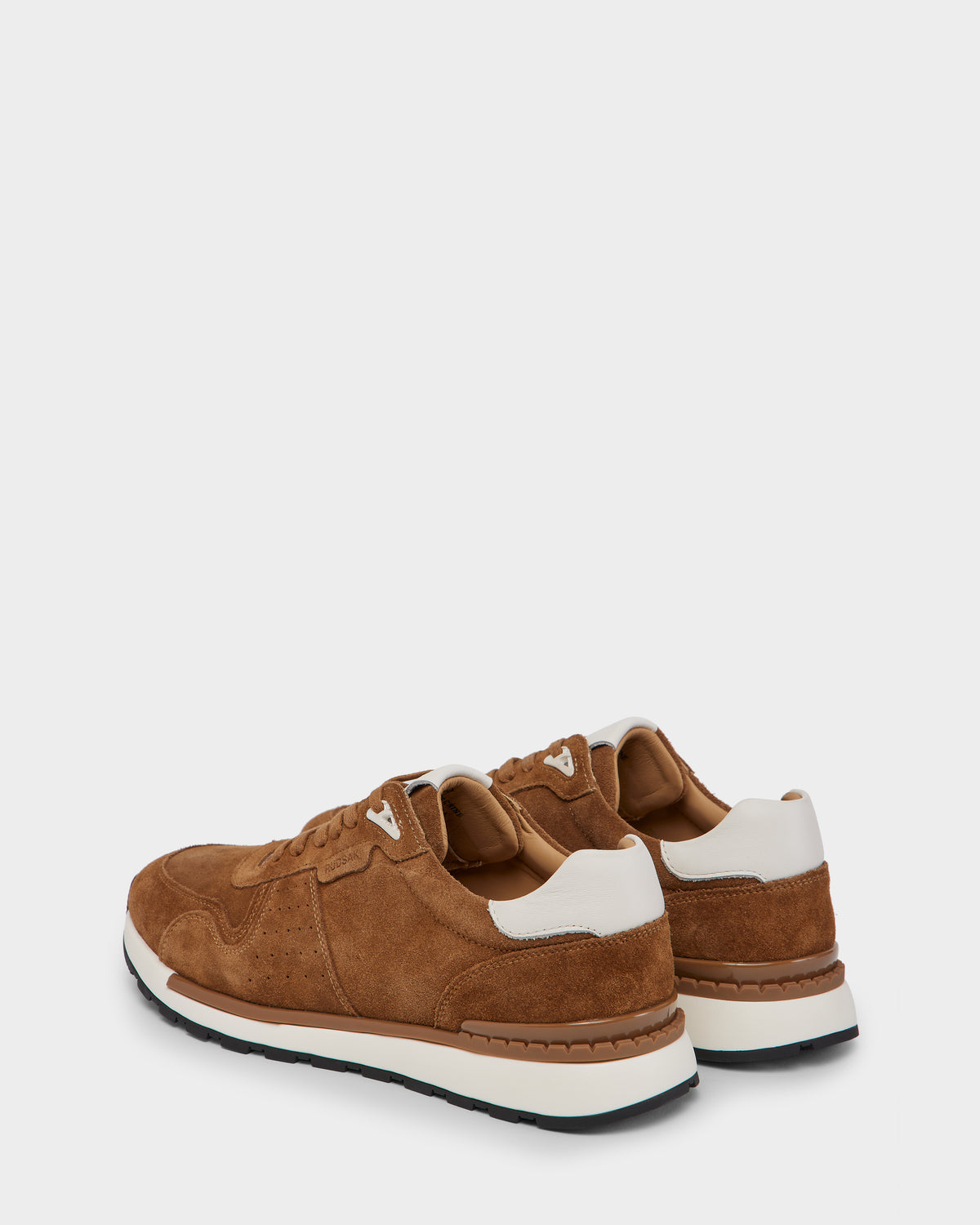 The Rudsak MALONE S - 6225002 Almond men’s suede sneakers in brown with white accents and black soles are shown from a rear side angle against a plain light gray background, highlighting their modern design.