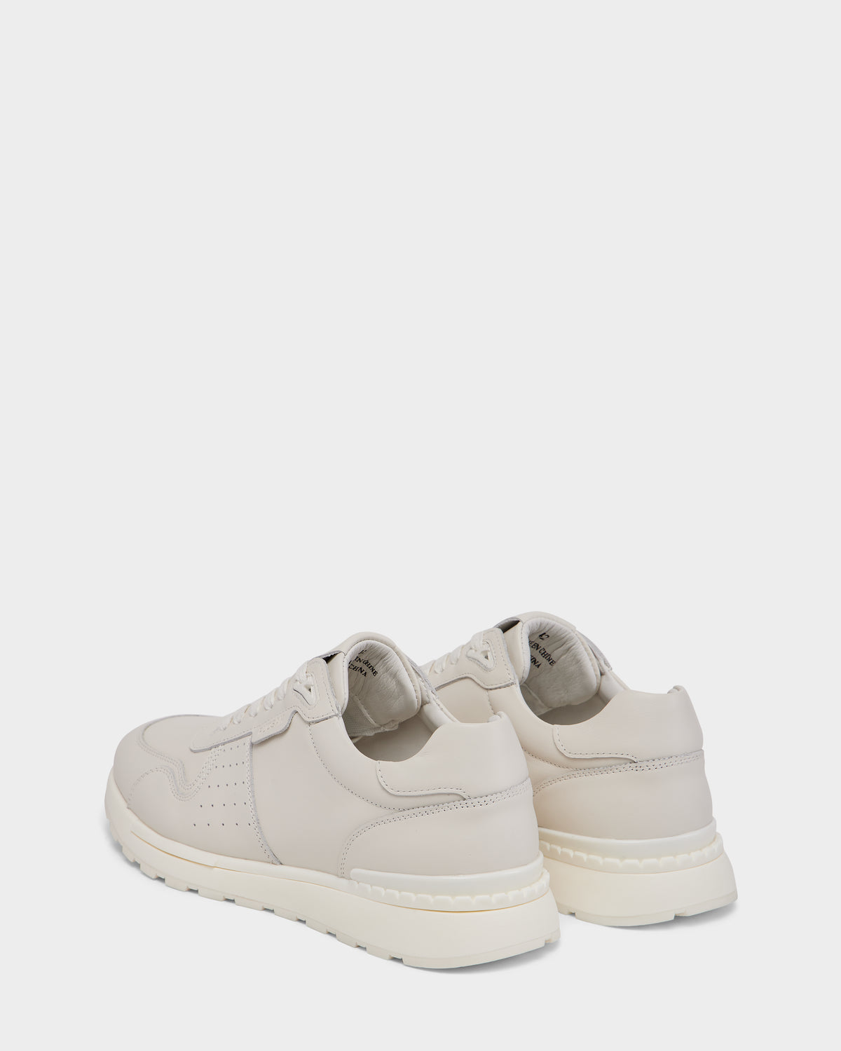 The Rudsak MALONE - 6225010 Iceland men’s leather sneakers in light beige feature white, textured soles, laces, and perforated details. Shown from the back and side on a plain white background. Fashioned from premium materials for everyday wear.