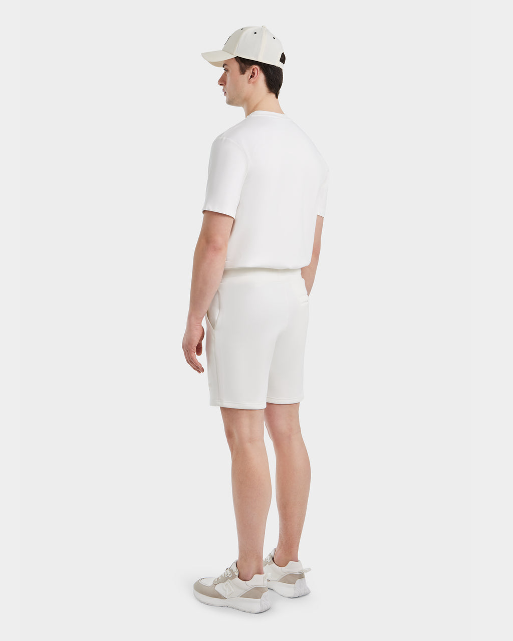 A man, seen from behind against a white background, wears Rudsak’s PASCAL - 6524022 ICELAND men’s double jersey shorts, a white polo shirt, white baseball cap, and Rudsak sneakers with beige details.
