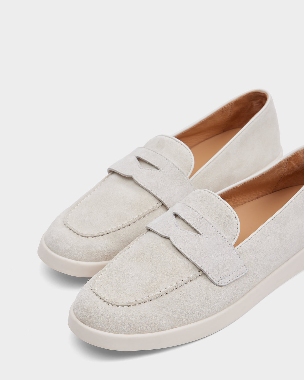 The RABECCA - 8225006 Iceland by Rudsak are light beige suede loafers with rounded toes, decorative top straps, white rubber soles, and light brown linings—luxury women’s footwear shown on a plain white background.
