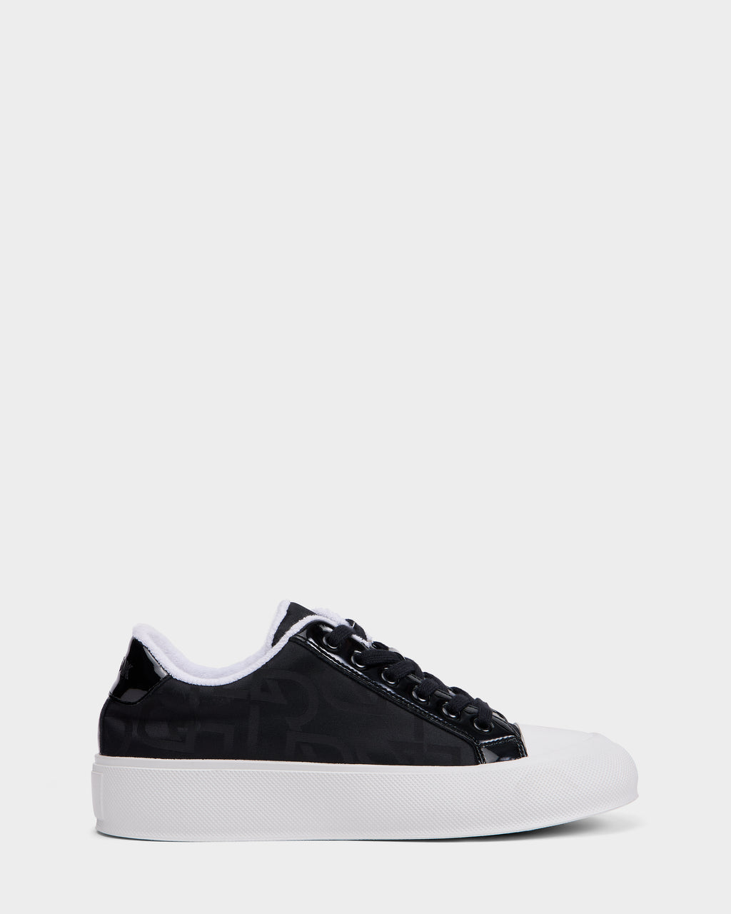 The Rudsak RIMA - 8225001 Black Pattern is a women’s black low-top platform sneaker with black laces, a white inner lining, and a thick white rubber sole, shown on a plain light gray background.