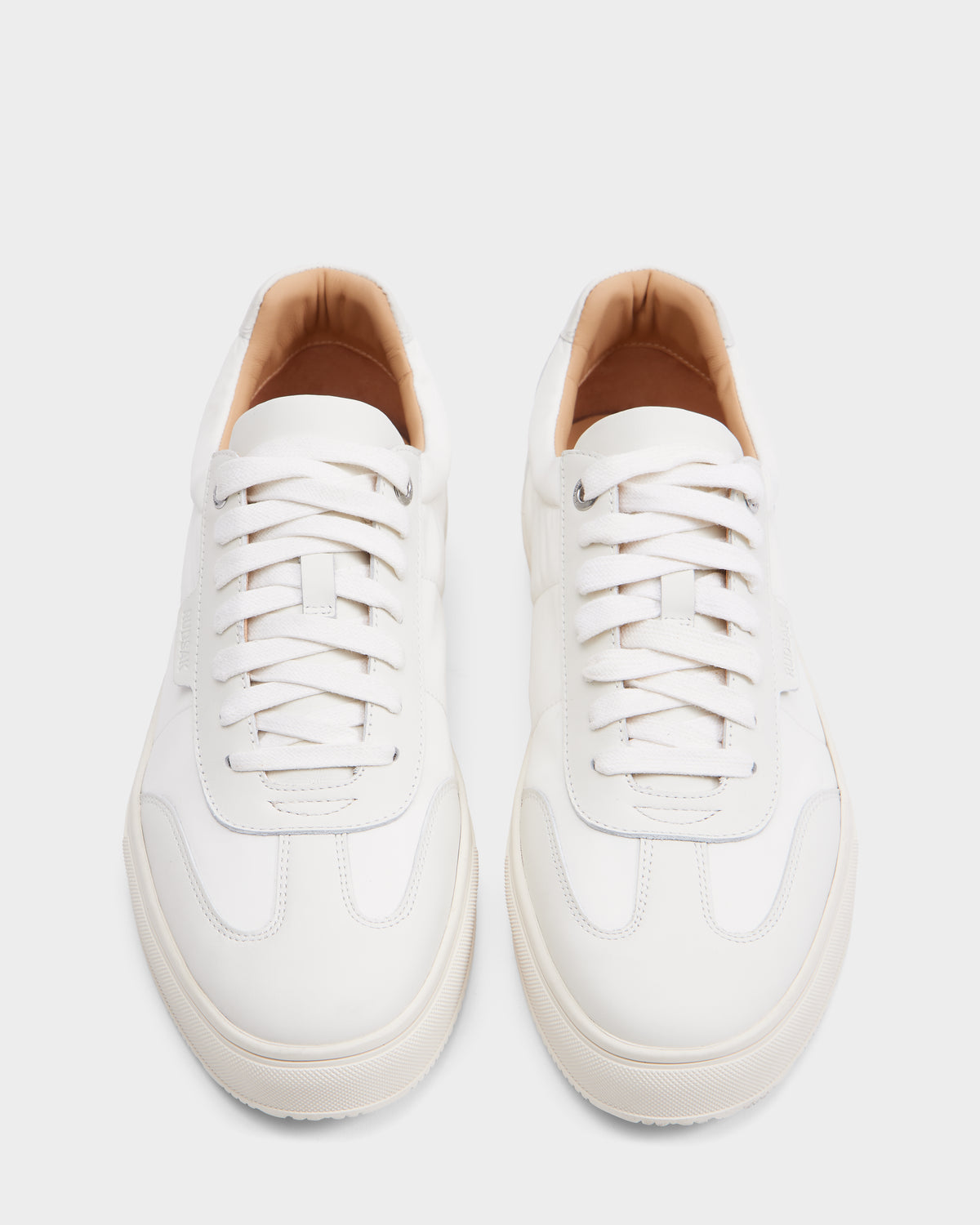 The Rudsak SKYLER - 6225003 Iceland is a minimalist men’s leather sneaker in crisp white, featuring white laces and a beige inner lining, shown side by side on a plain white background.