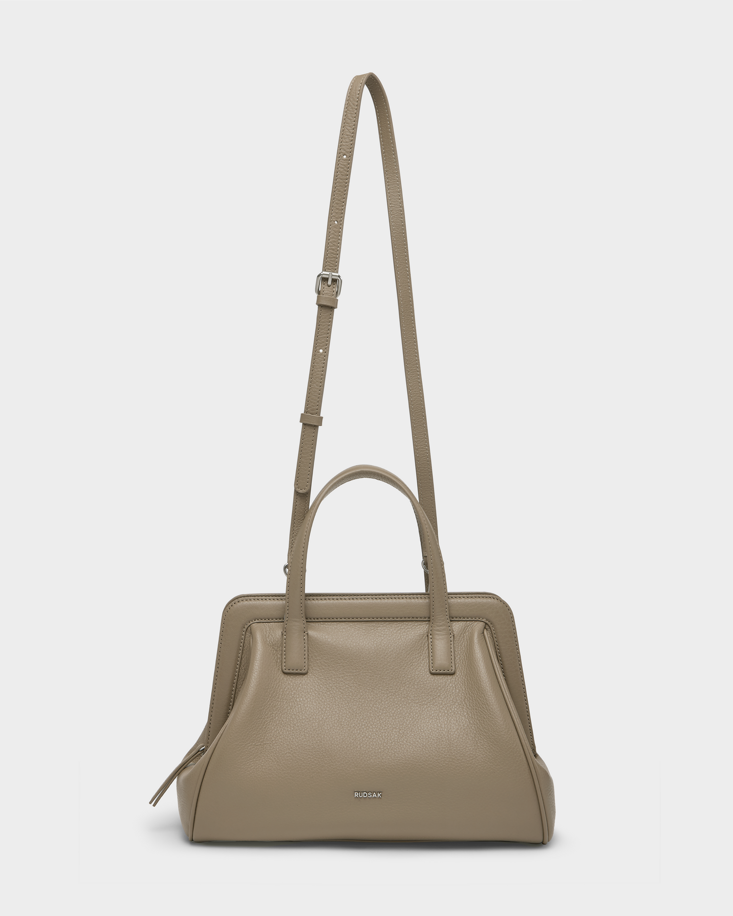 The Rudsak TAULLA - 8325002 Almond is a taupe pebble leather women’s satchel with double handles and a removable shoulder strap, subtle silver hardware, a small logo front, and a roomy interior for daily essentials.