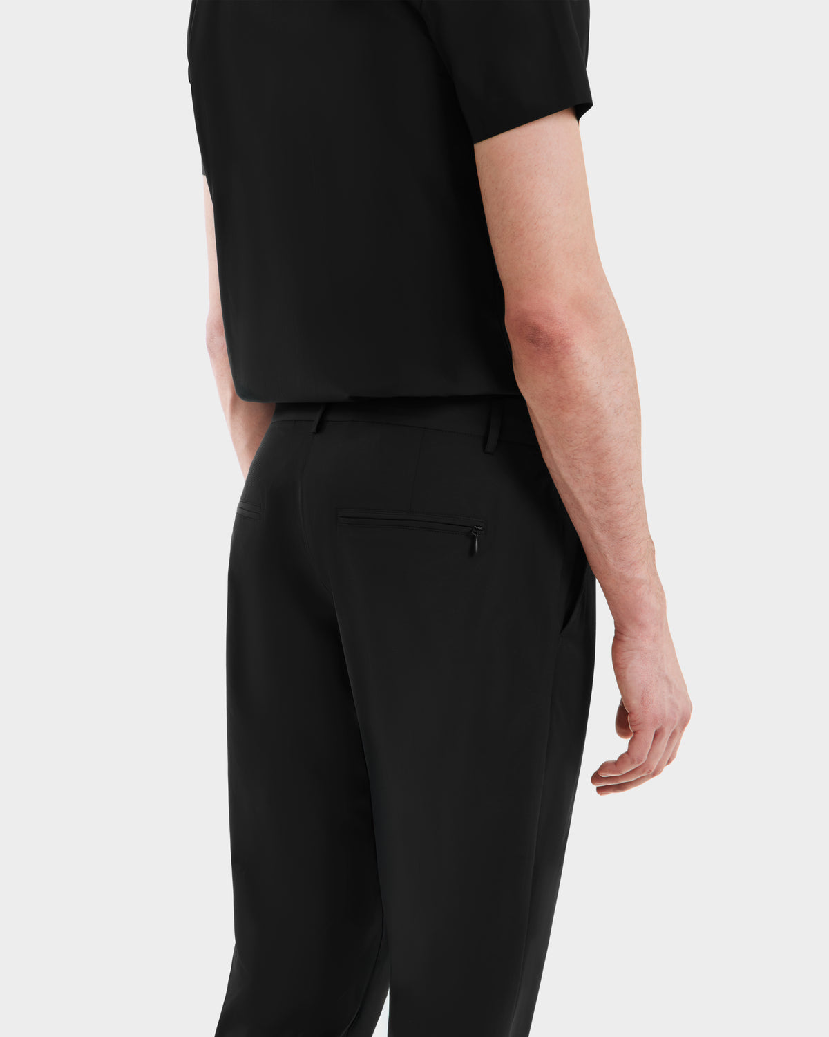 A person is seen from the back wearing the Rudsak VERNON - 6525025 Black shirt and tapered-leg trousers, with their right arm at their side against a light gray background.