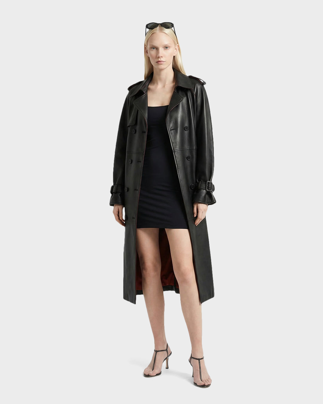 A woman in sunglasses, a Rudsak CASSIE L-B - 8125553 Black trench coat, a short black dress, and black heeled sandals stands facing forward against a plain light background.