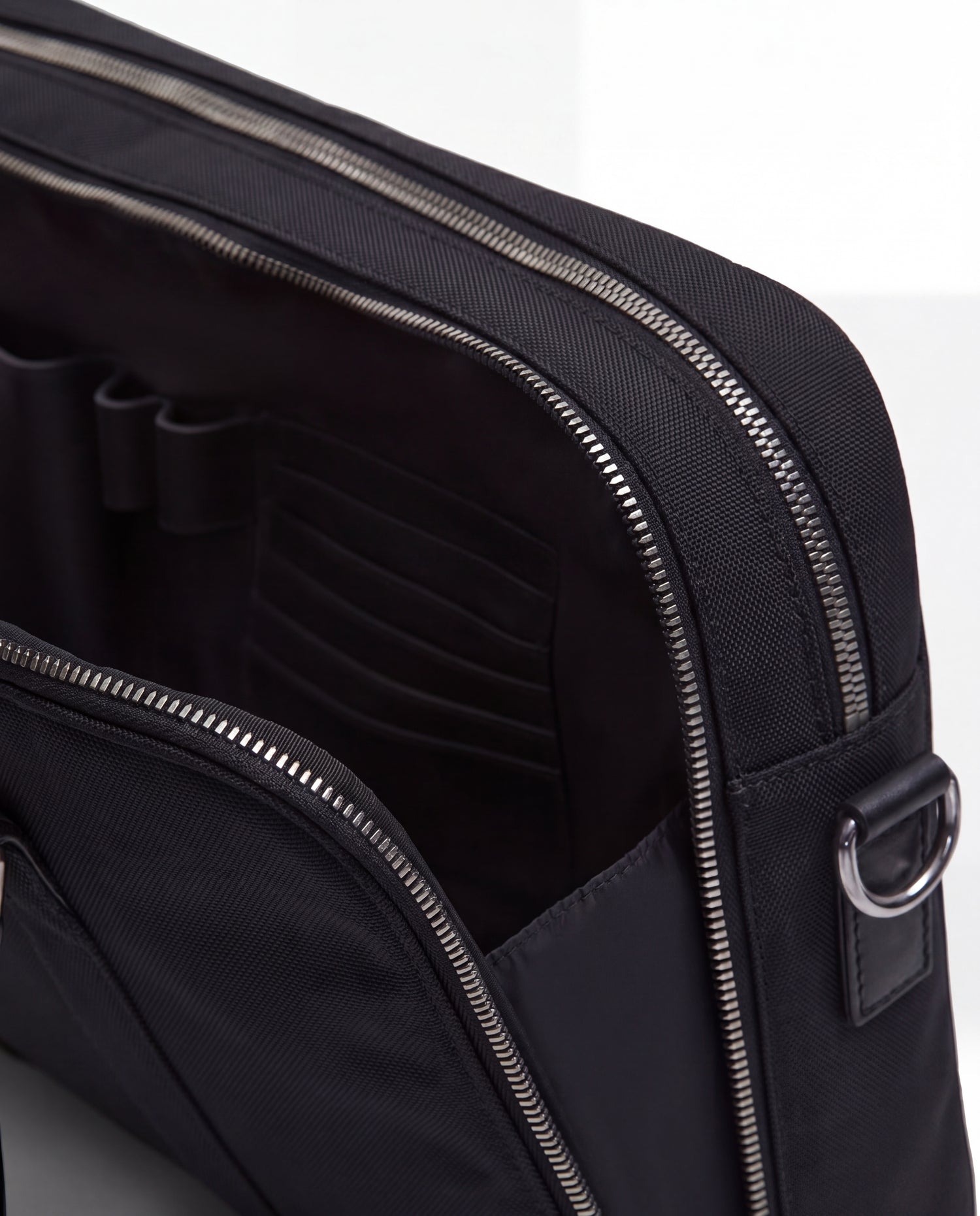 Close-up of the Rudsak HENRY N - 9326056 Black bag featuring a zippered pocket partially open to reveal organized interior compartments and slots.