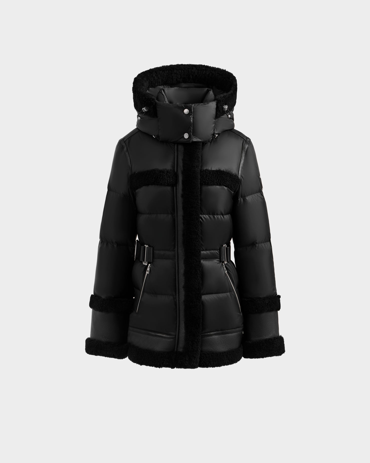The Rudsak TESSA - 8125615 Black is a women’s down puffer jacket with a hood, front zipper, belted waist, zippered pockets, and luxe shearling trim—an elegant winter essential shown on a plain light background.