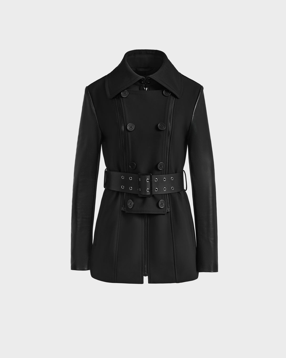 The VIRGINIE S - 8125053 Black by Rudsak is a tailored black trench coat with a wide collar, double-breasted buttons, long sleeves, and a matching belt with metal eyelets and a rectangular buckle, shown on a plain white background.