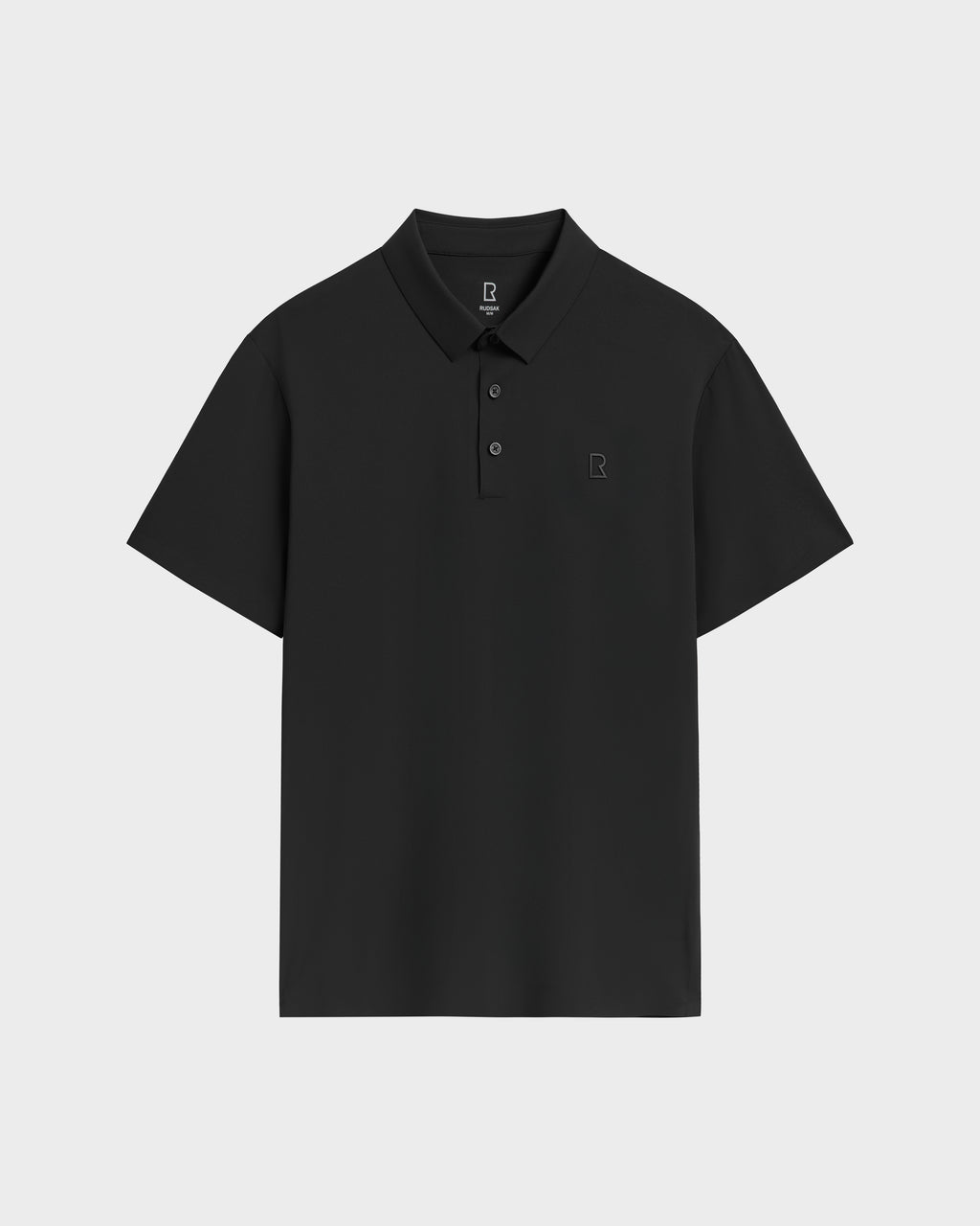 The Rudsak WELLS - 6525017 Black is a mens essential: a tailored-fit, plain black polo with short sleeves, three-button collar, and small square logo on the left chest. Made from lightweight technical fabric. Displayed on a light gray background.