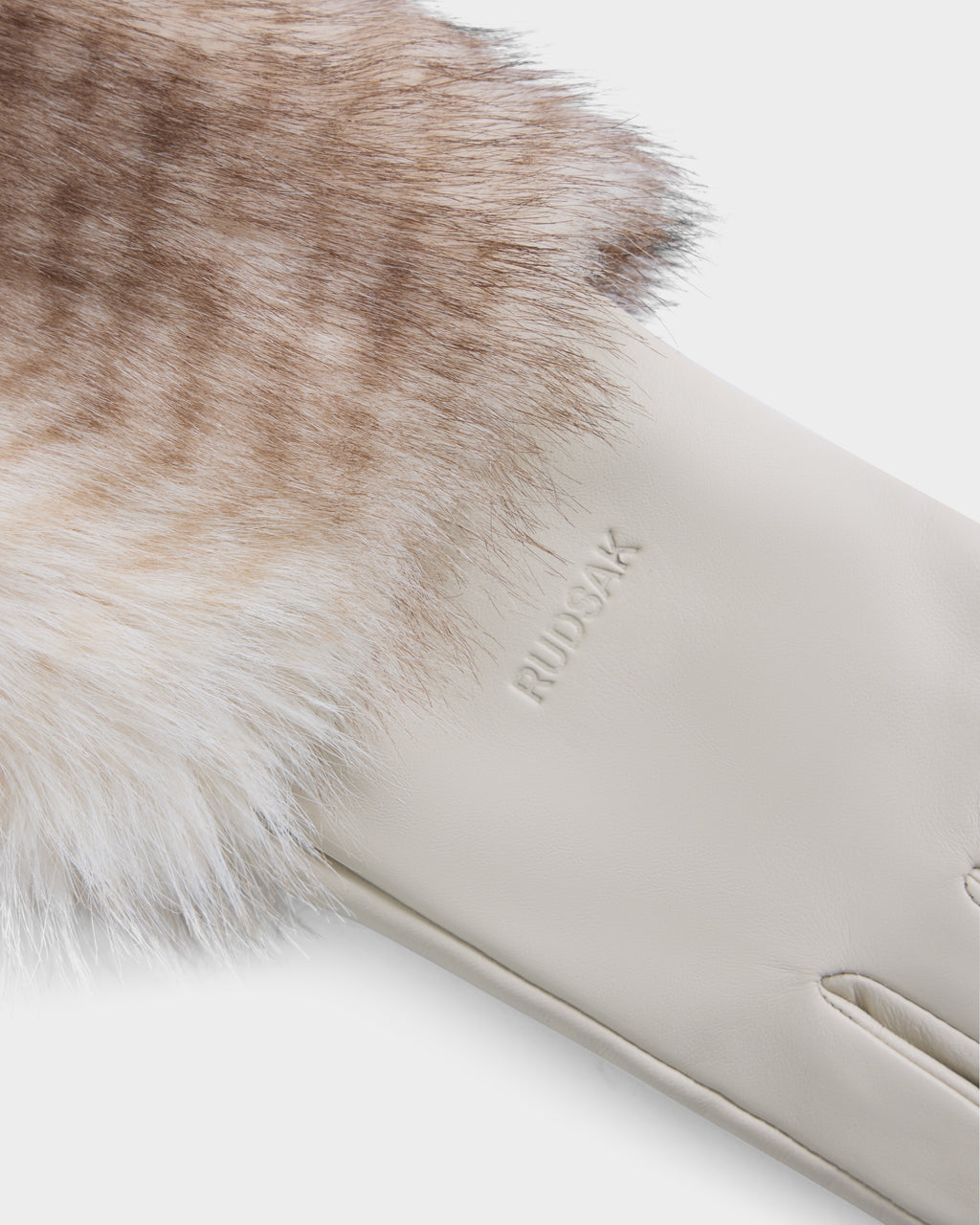 A close-up of the ZAYLA - 8426712 Vanilla glove by Rudsak, crafted from cream-colored leather with soft brown-and-white fur trim. The brand name “RUDSAK” is embossed on the leather near the wrist.