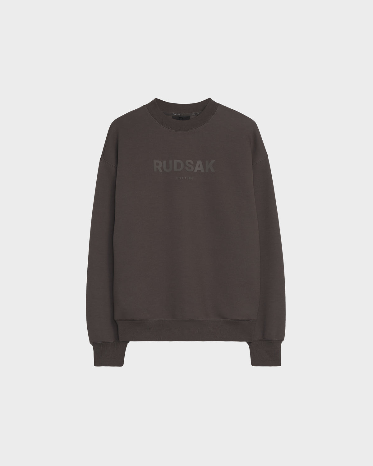 The BRYN - 9524007 Grey W by Rudsak is a relaxed-fit, grey cotton crewneck sweatshirt with long sleeves, ribbed cuffs and hem, genderless sizing, and RUDSAK subtly printed in large letters across the chest.