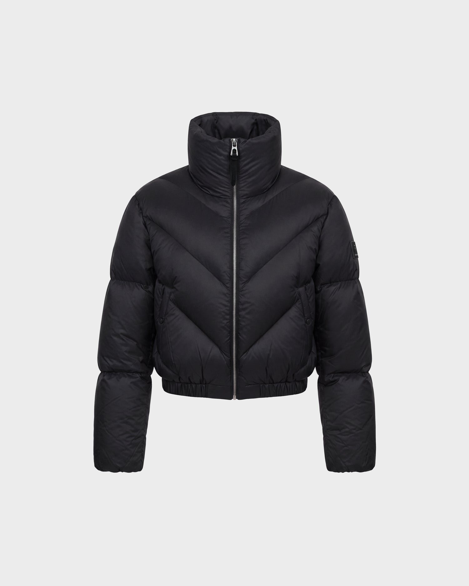 A black, cropped puffer jacket by Rudsak (ANSLIE - 8126986 Black) with a high collar and front zipper, displayed on a plain light gray background. The jacket features horizontal and diagonal quilted patterns.