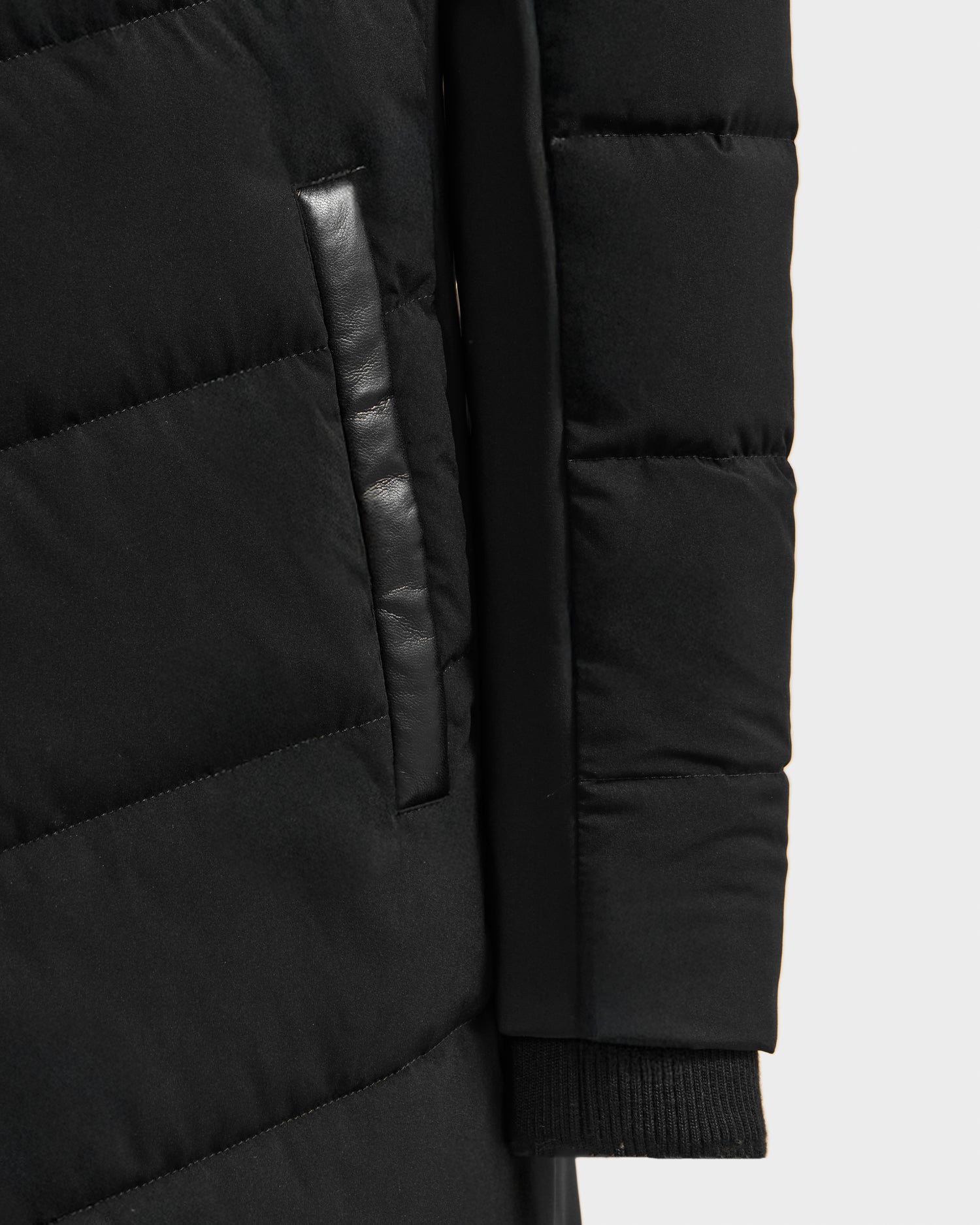 Close-up of the Rudsak LAUREN - 4124520 Black quilted down coat, highlighting a leather-trimmed side pocket and a sleeve with ribbed knit cuff.