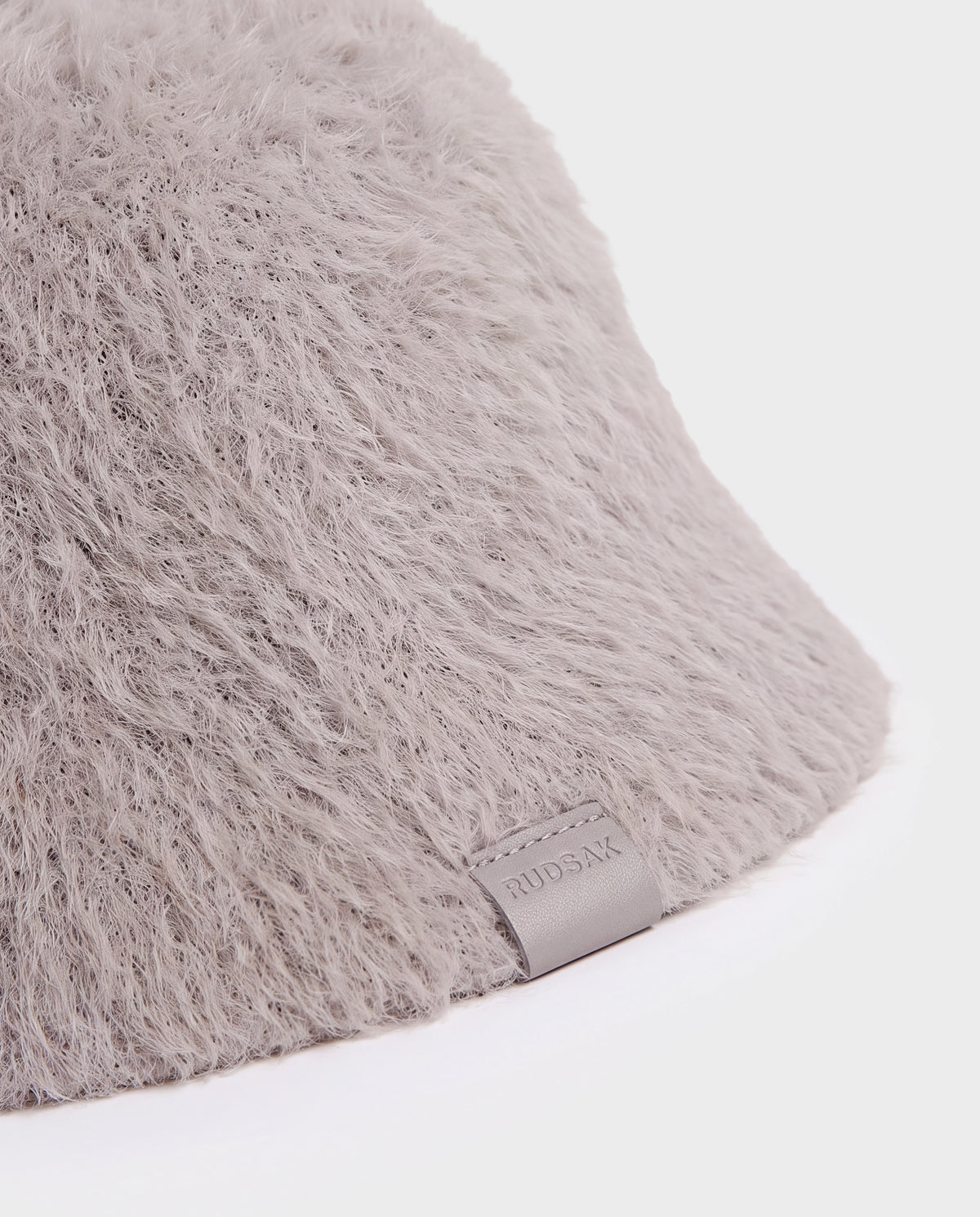 Close-up of a light gray fuzzy nylon-blend Rudsak MAIE - 8426517 Cement bucket hat featuring a small branded leather tag.