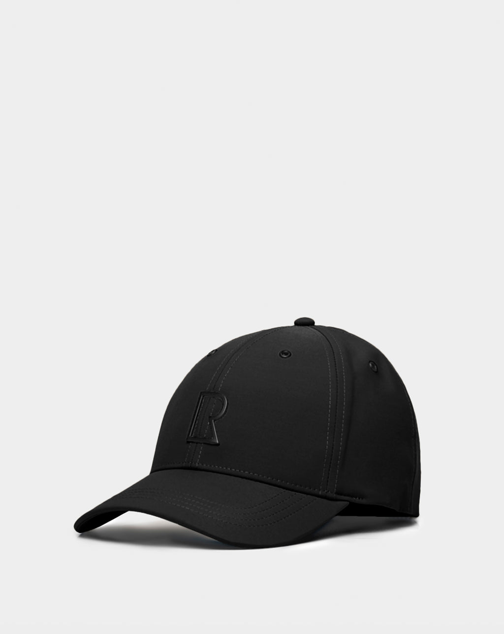The ARSENE - 9422504 Black by Rudsak is a unisex adjustable black baseball cap with a curved brim and embossed capital R on the front, shown against a plain light gray background.