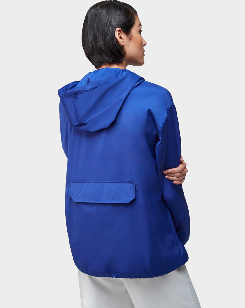 Seen from behind, a person with short dark hair models the Rudsak STALENS - CA EN 9520000 ROYAL BLUE hoodie windbreaker in a loose fit, paired with white athleisure pants, set against a plain light background.