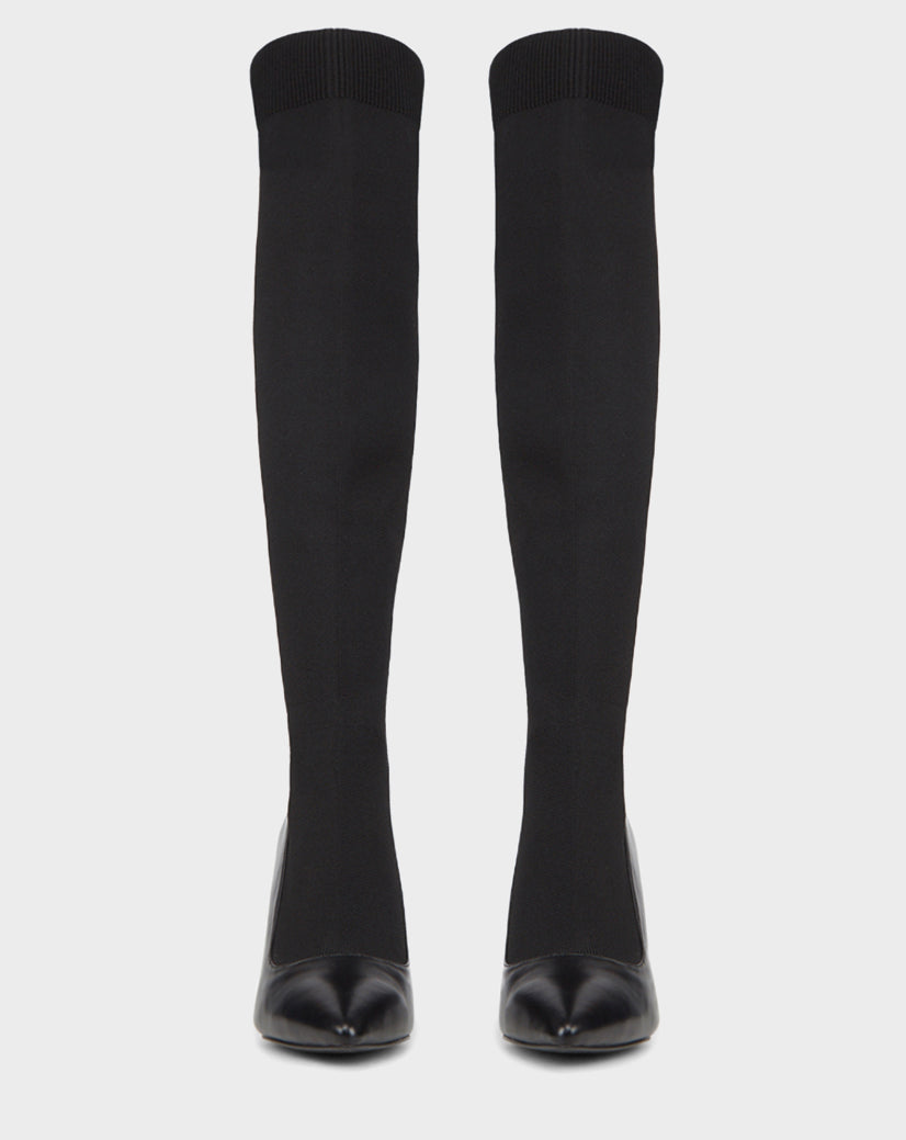The TIGRIS - CA EN 8218532 BLACK boots by Rudsak are black knee-high statement boots with a ribbed top and pointed toe in stretch fabric, displayed upright against a white background.