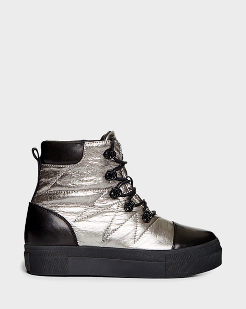 The TASSEL - CA EN 8219514 SILVER by Rudsak is a metallic silver high-top sneaker with black accents, black laces, a thick black sole, and quilted stitching details, shown on a plain light gray background.