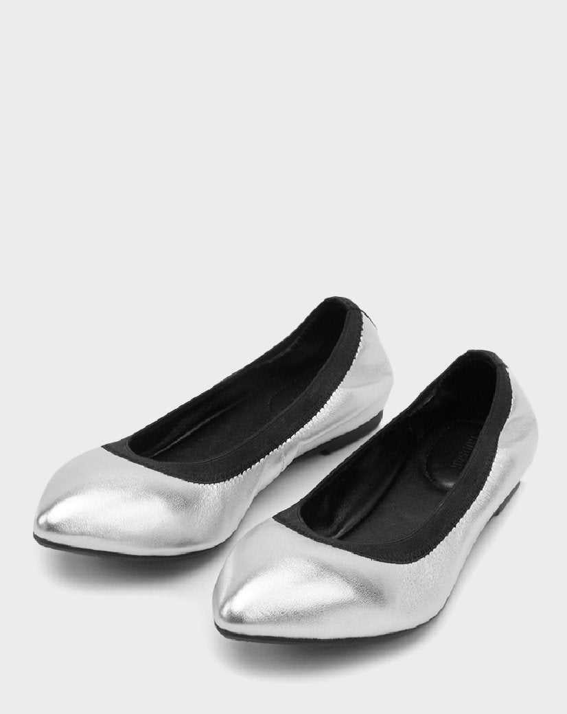 The Rudsak TESSALY - CA EN 8220037 SILVER ballerina flats feature sleek silver leather, black interiors, rounded toes, and a minimalist design, elegantly displayed on a light background.