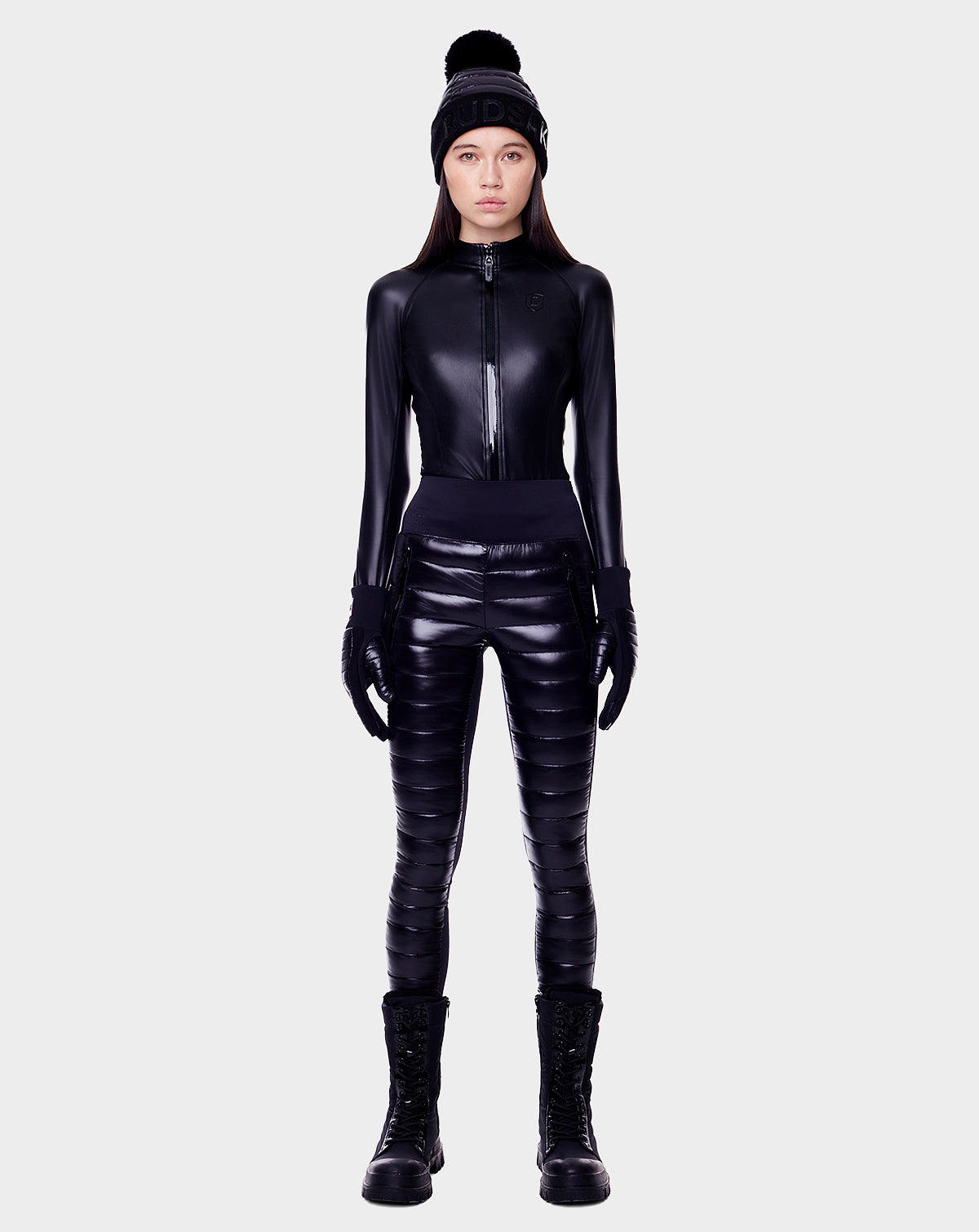A woman in a black outfit flaunts chic après-ski style, highlighted by Rudsak’s ARIL - 8522520 BLACK women’s pant filled with sustainable Sorona.
