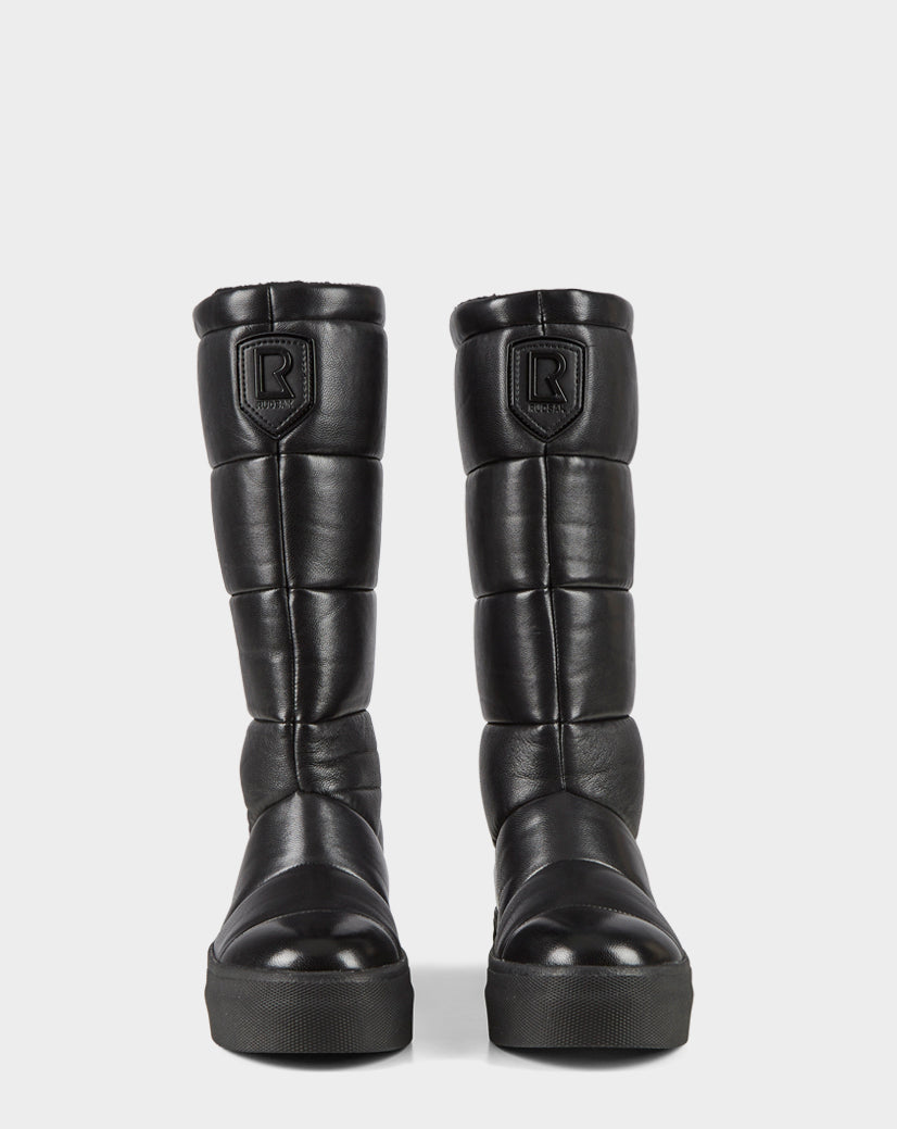 The Rudsak TEIGEN - CA EN 8220533 BLACK boots are black, knee-high, quilted leather with thick soles and a raised R logo on the front, shown against a plain white background.