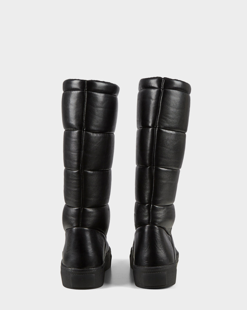The TEIGEN - CA EN 8220533 BLACK boots by Rudsak are tall, black knee-highs with chunky soles and quilted leather puffer design, displayed from the back on a plain white background.