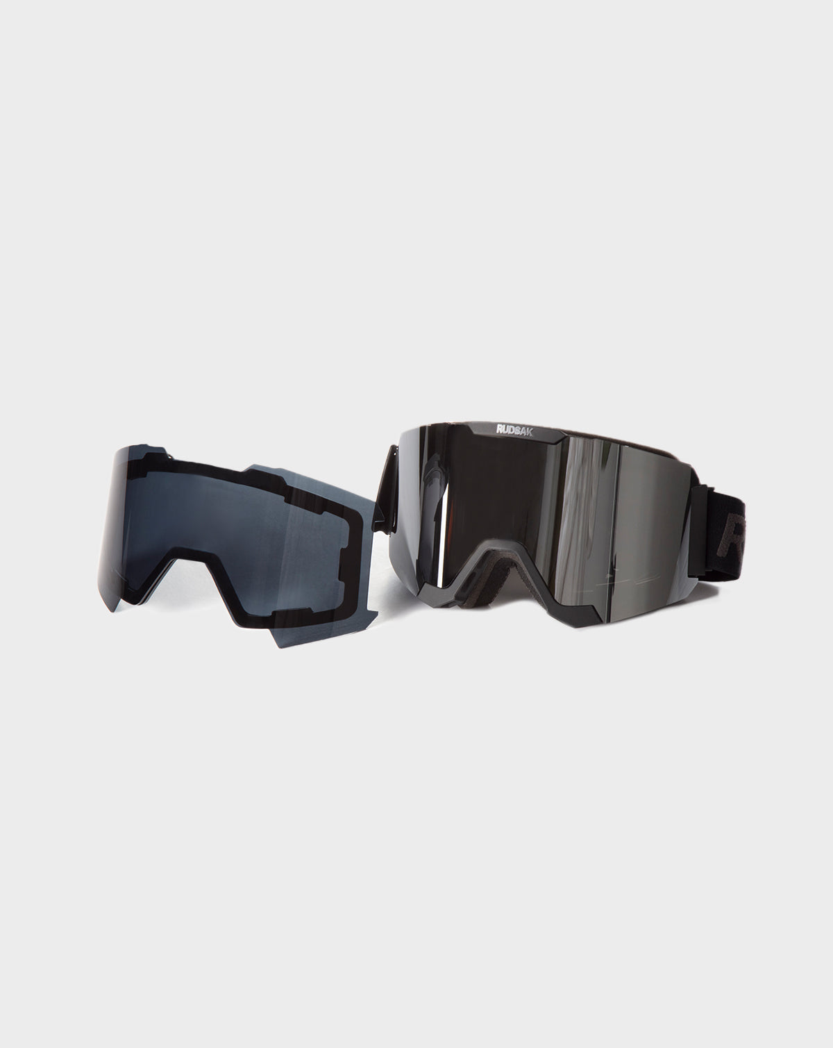 The Rudsak PEAK - 9421515 BLACK ski goggles feature a reflective lens, adjustable strap, and come with an extra interchangeable dark-tinted lens, displayed on a plain light background.